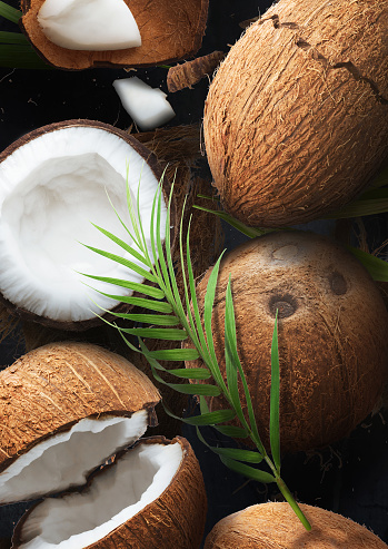 A lot of fresh raw coconuts with palm leaves over dark marble background. High resolution image, 3d conception