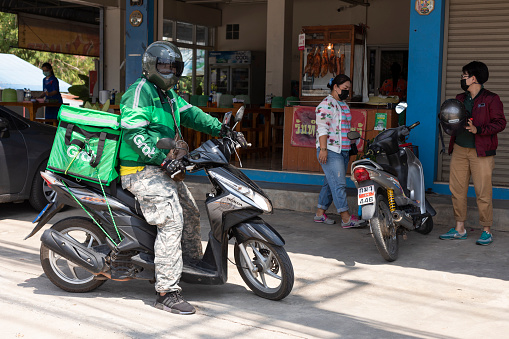 Mae Sot, Tak, Thailand - May 16, 2021 : Unidentified Thai man working as part of Grab food delivery sending food to customers at Mae Sot, Tak, Thailand.