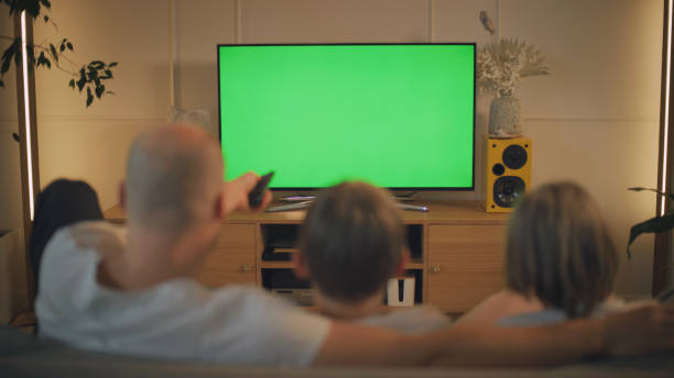istock Screen time during pandemic. Father and sons watching TV. Chroma key on the screen 1322336056