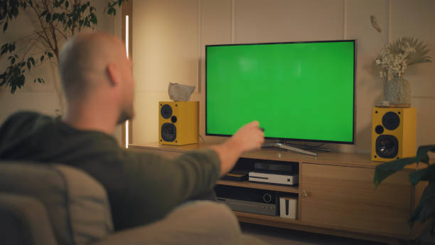 istock Screen time at home. Man relaxing while watching TV. Chroma key in the screen 1322336132