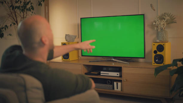 istock Screen time at home. Man relaxing while watching TV. Chroma key in the screen 1322336144