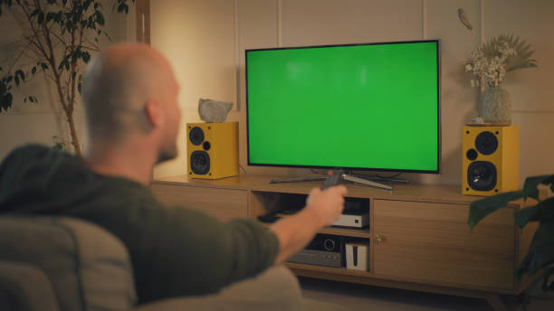 istock Screen time at home. Man relaxing while watching TV. Chroma key in the screen 1322336158