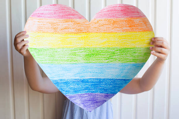 istock girl holds a rainbow heart in her hands, on a light background 1322342021