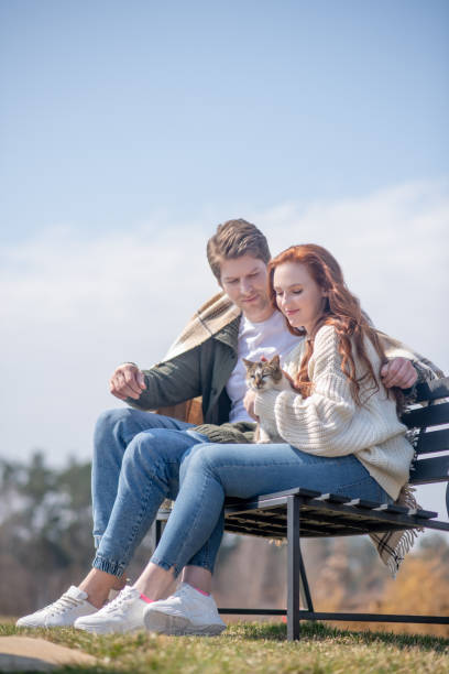 istock Man and woman with cat sitting on bench 1322342066