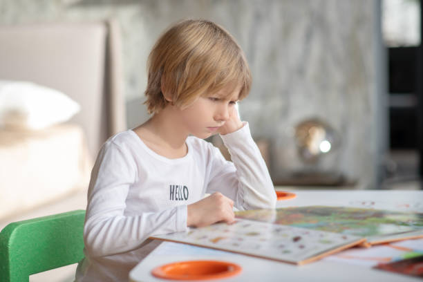 istock Bored young boyreading a book at home 1322342852