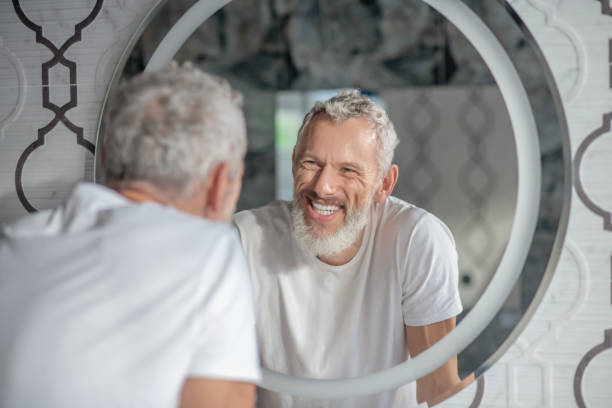 istock Smiling grey-haired man looking at the mirror 1322342856