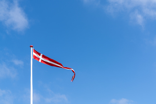 A Danish banner flag waving in the wind under a blue sky with copy space