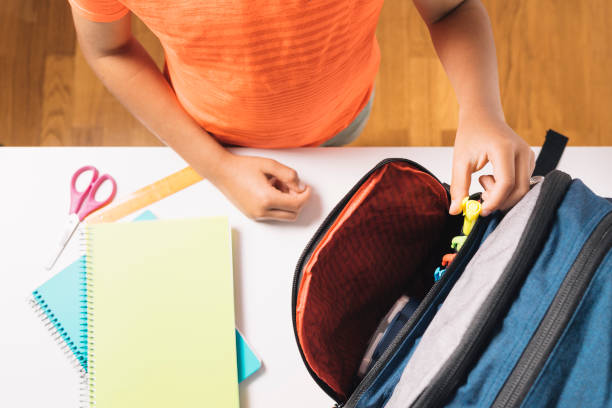 Top view of a child taking a color from his school bag to start class. stock photo