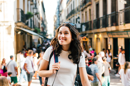 Happy young tourist woman visiting the lively Old Town of San Sebastian, Spain, in summer