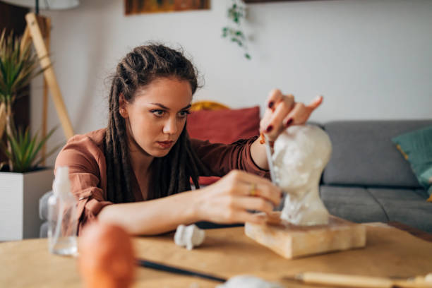 istock Artist with dreadlocks measuring proportions for her clay sculpture 1322355667
