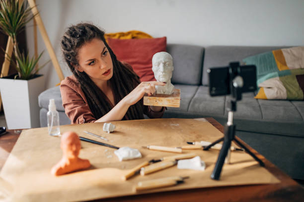 istock Female vlogger showing her audience how with a help of clay, work tools and some creativity can make some interesting stuff for home decor 1322357901