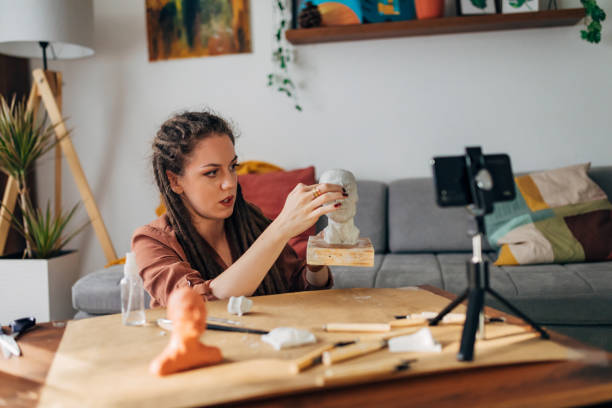 istock Joyful female vlogger using her free time to record an online tutorial about easy DIY clay sculpting from her modern home 1322357909