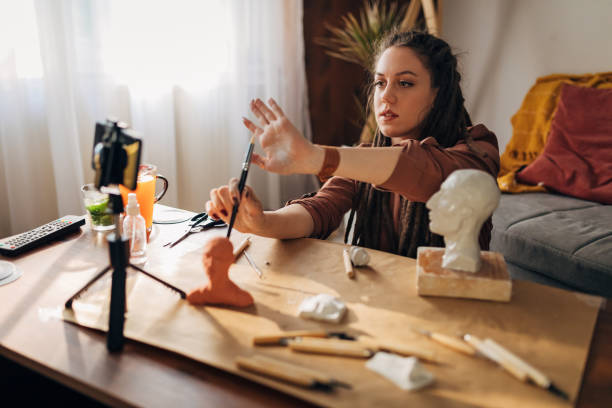 istock Female sculptor, while recording her DIY tutorial, showing to her followers which brushes and hand tools she using for clay sculpting 1322357987