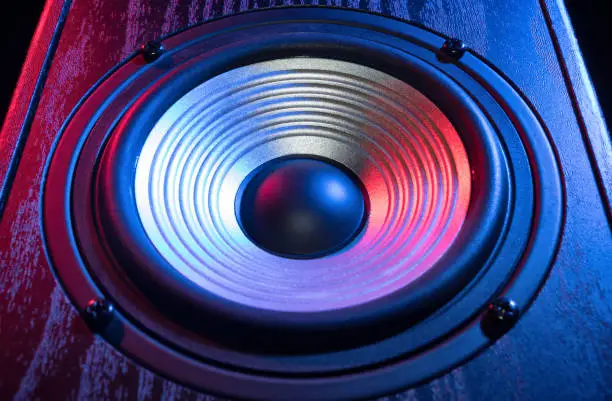 Detail of sound speaker in neon light on black. Close-up.