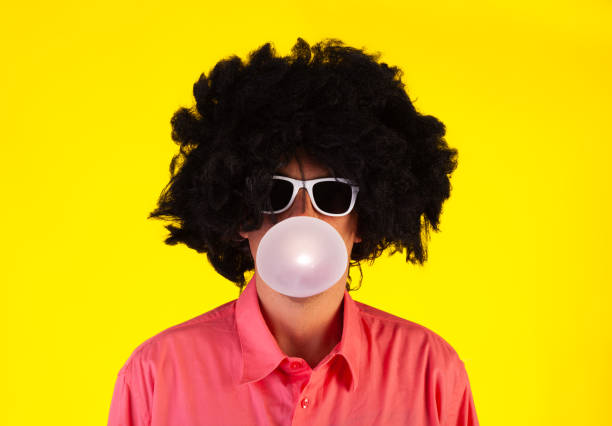 istock Curly man wearing sunglasses blowing bubble with chewing gum 1322361071