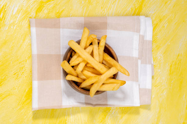 french fries in a wooden bowl. space for copying text, copyspace. yellow background