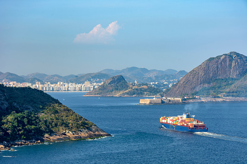 Cargo ship entering Guanabara Bay through the mountains and forests of Rio de Janeiro with the city of Niteroi in the background