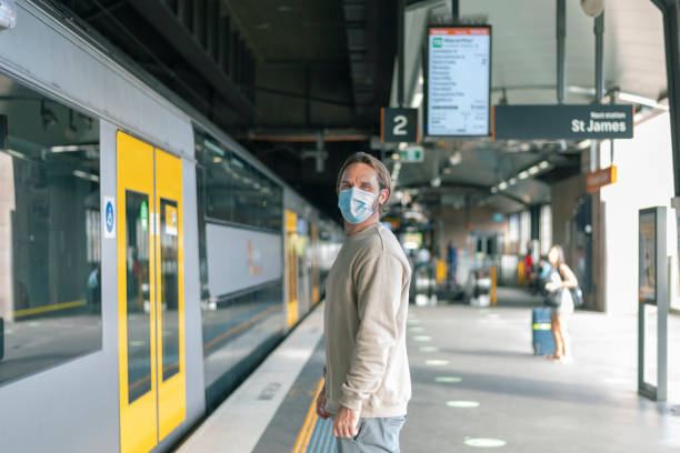istock Male wearing face mask waits on platform to board train 1322364188