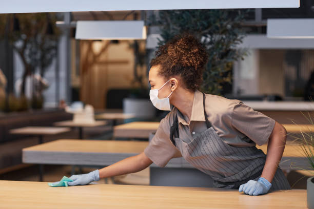 istock Woman Sanitizing Tables in Cafe Side View 1322365282