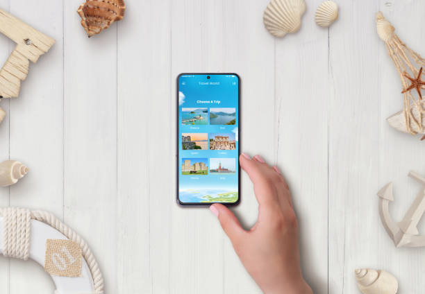 istock Smart phone on desk with travel destinations app. Plan a trip concept. Top view, flat lay. 1322367305
