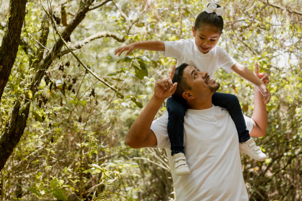 latijnse vader die zijn dochter op zijn schouders draagt-familie die in de park-vader loopt die met zijn dochter in het park speelt - latijns amerikaans en hispanic etniciteiten stockfoto's en -beelden