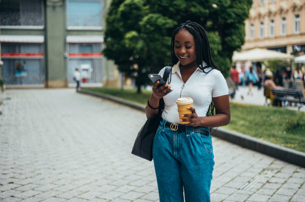 istock African american woman using smartphone and drinking coffee takeaway 1322367897