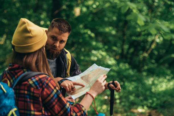 istock Couple of hikers using trekking poles and map while spending the day in nature 1322367930
