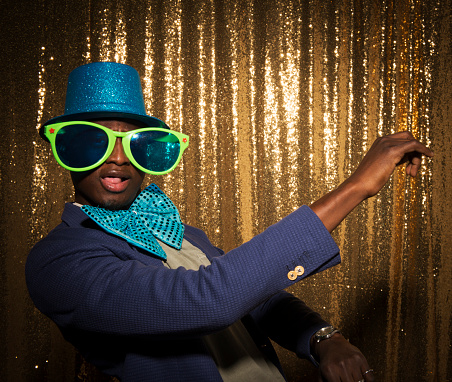 Portrait of young man wearing an oversized funny glasses and hat while posing at photo booth during the party.