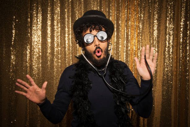 Portrait of man wearing funny props and taking photos at photo booth during the party.