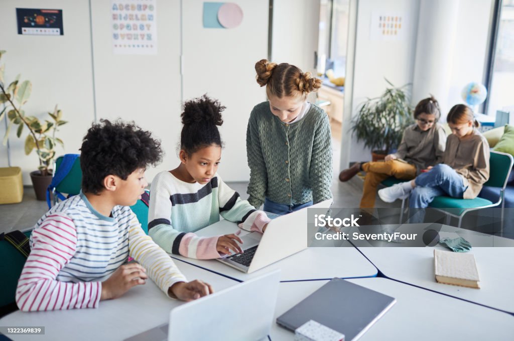 Group of Kids in Modern School High angle view at diverse group of children working together at desk in classroom at modern school, copy space Child Stock Photo