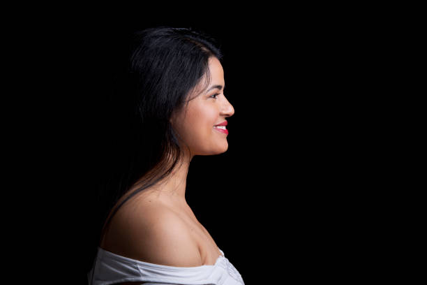 Beautiful woman portrait front of gray background. She is sitting on chair and looking her side away.