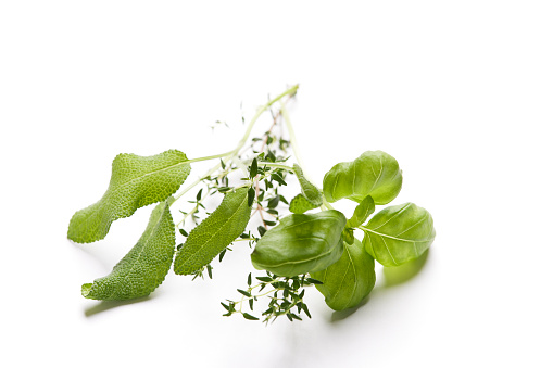 Thyme, sage and basil leaves on a white background.