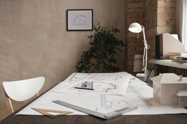 Empty minimalistic office with plant near wall, blueprints, rulers, lamp and D model of building on table Empty minimalistic office with blueprints on table architect office stock pictures, royalty-free photos & images