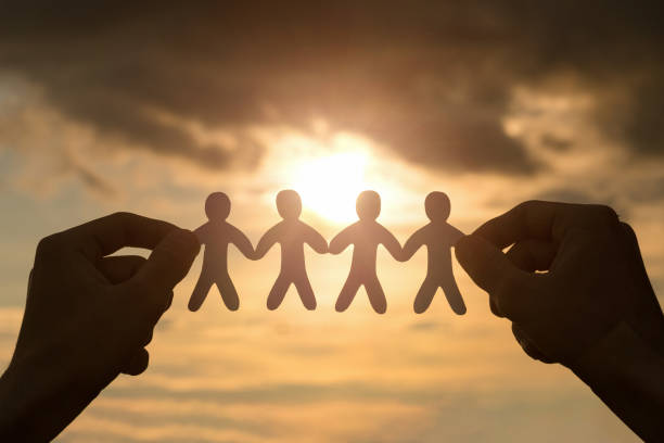 istock Hands hold a group people on the background of the sun. 1322370991