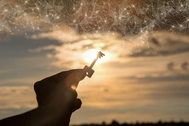 hand holds a key on the background of a sunset. - destrancar imagens e fotografias de stock