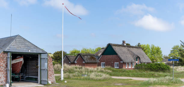 ファノ島の前景にある典型的な赤レンガのデンマークの家とボートハウスと旗 - denmark house flag danish flag ストックフォトと画像