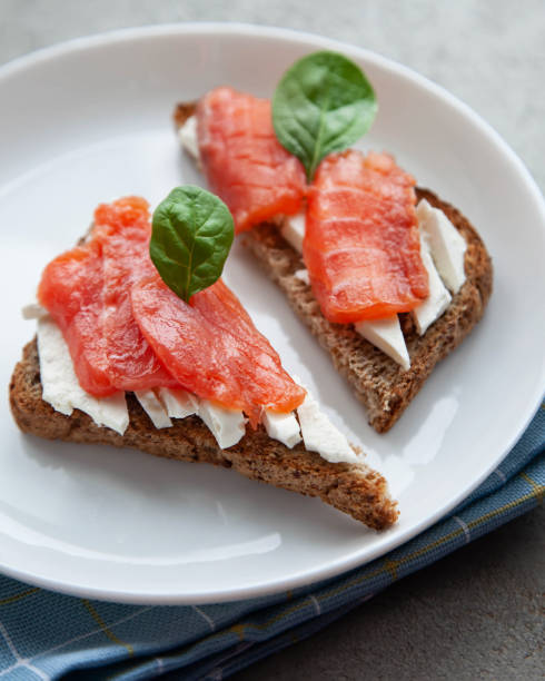 istock Bruschetta with red fish and cream cheese with black bread on white plate. 1322374716