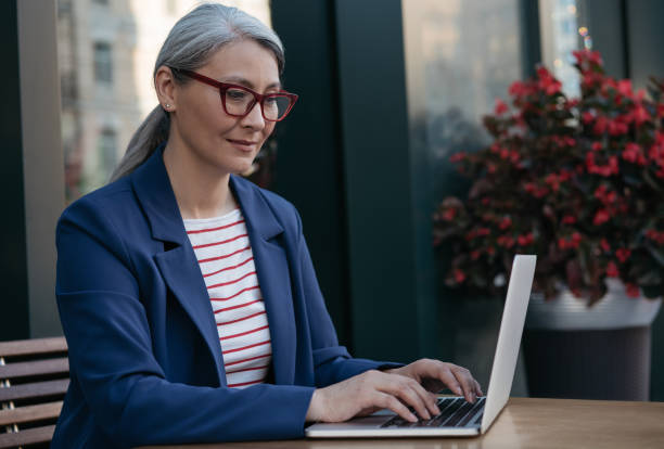 Mature businesswoman using laptop computer, working online, typing on keyboard, edit something