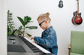 Eight year old boy imagine himself to be musisian, while playing electric piano
