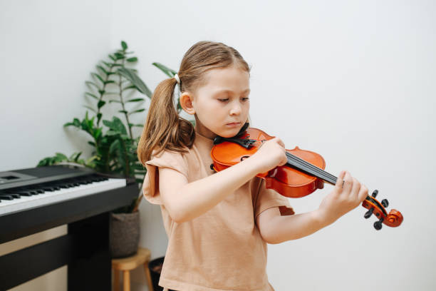 istock Focused little girl learning to play violin, hitting strings with her finger 1322376006