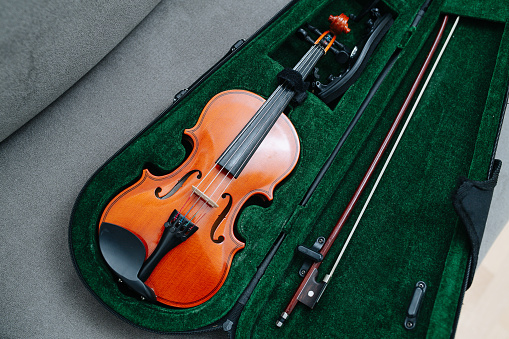 Violin, bow and support system gently placed in a case draped in yellow cloth. High angle.