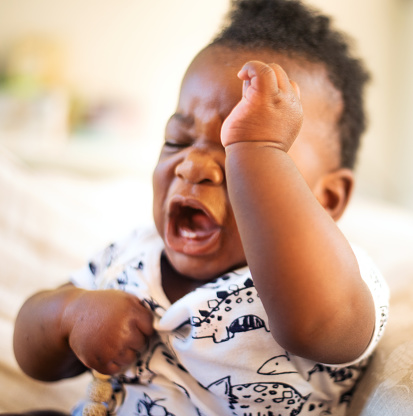 Close-up of a cute little African baby girl crying with her eyes closed at home