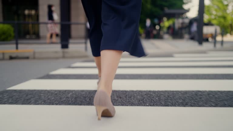 Close-up clip of businesswoman`s high heel shoes while crossing street in city