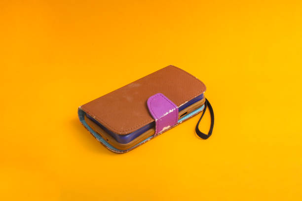 istock Old used brown phone case isolated on orange background 1322386116