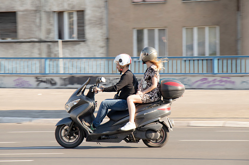 Belgrade, Serbia - June 5, 2021:  Couple riding on a scooter bike  , on city street on a sunny day