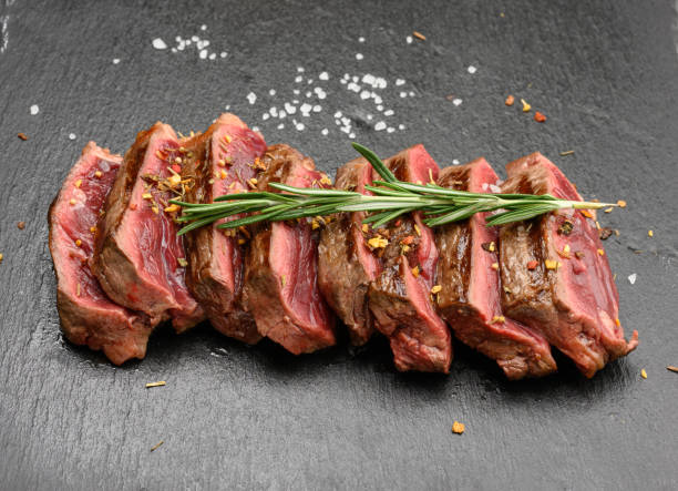 istock sliced fried beef steak New York  striploin on a black background with spices, degree of doneness rare 1322400992