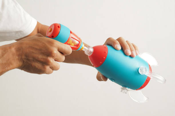 Close-up. Hands collect a toy blue spaceship rocket with the tool.