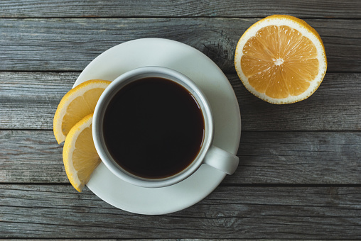 Coffee with lemon on gray wooden background, table top view