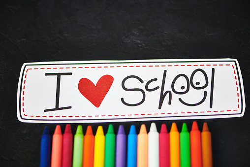 Colorful crayons with I Love School message on chalkboard background