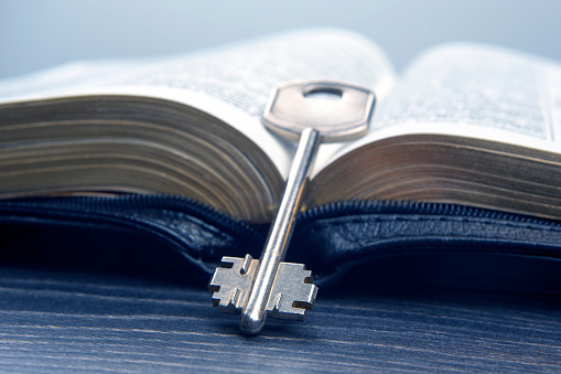 the key lies on an open bible book. metaphor for discovering wisdom through the study of religious literature